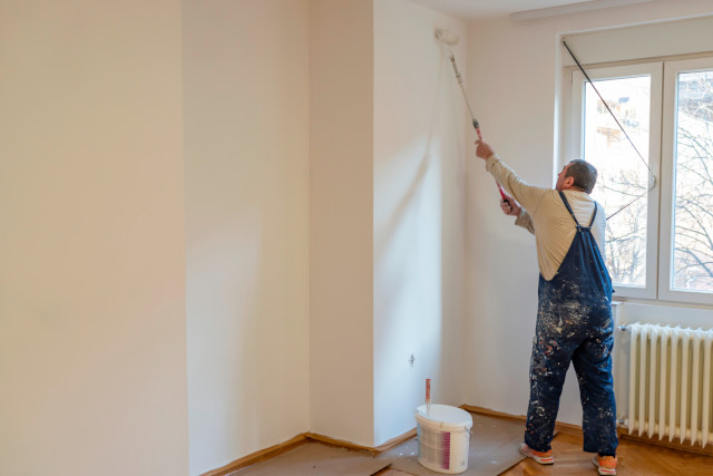 Fähiger Malprofis in Fribourg streicht eine Wand.