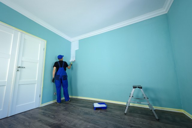Maler streicht die Zimmerwände neu